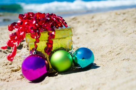 Gift box with christmas balls on the beach by the ocean - holiday conceptの写真素材