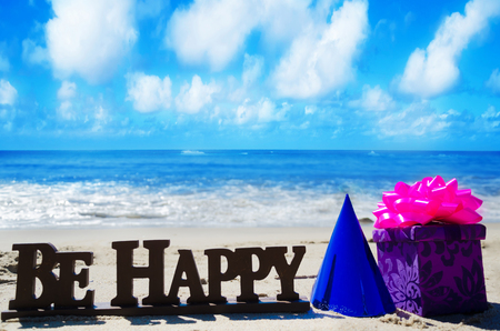 Sign "Be Happy" with Birthday decorations on the sandy beach by the oceanの写真素材