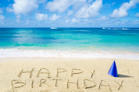 Sign "Happy Birthday" with hat on the sandy beach by the oceanの写真素材
