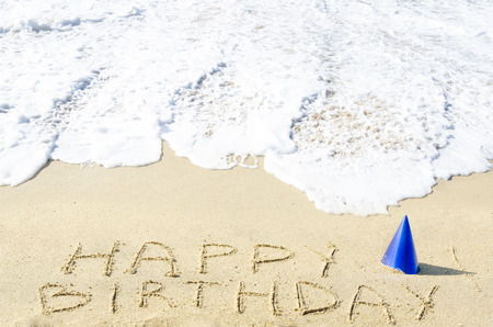 Sign "Happy Birthday" with hat on the sandy beach by the oceanの写真素材
