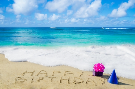 Sign "Happy Birthday" with decoration on the sandy beach by the ocean の写真素材