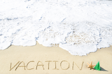 Sign "Vacation" on the sandy beach by the oceanの写真素材