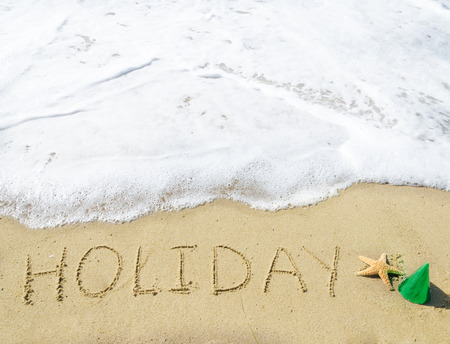 Sign "Holiday" on the sandy beach by the oceanの写真素材