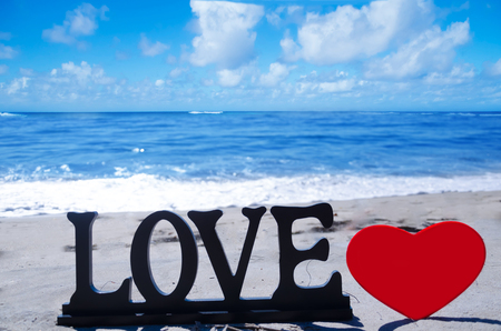 Sign "LOVE" with heart shape on the sandy beach by the oceanの写真素材