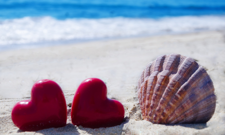 Seashell with two hearts  on the sandy beach by the oceanの写真素材