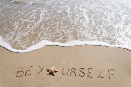 Sign"Be Yourself" with starfish on the sandy beach by the oceanの写真素材