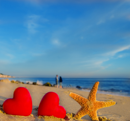 Starfish with hearts on the sandy beach by the oceanの写真素材