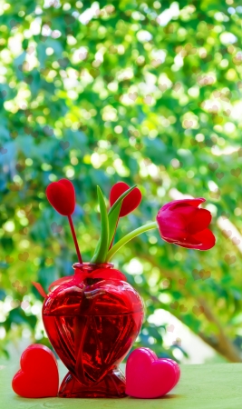 Red Tulip with two hearts in the vase on the natures background with bokehの写真素材
