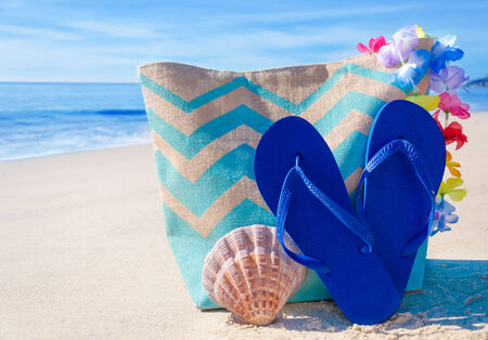 Beach bag with seashell and flip flops by the oceanの写真素材