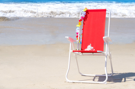 Beach chair with seashell on the sandy beach by the oceanの写真素材