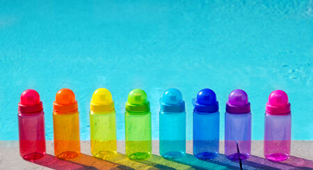 Color water bottles by the swimming pool in sunny day