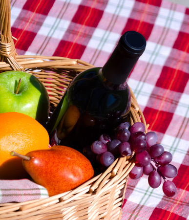 Picnic basket with fruits and wine on the tableの写真素材