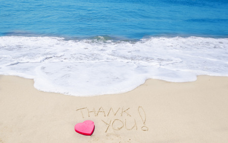 Sign "Thank you" on the sandy beach next to oceanの写真素材