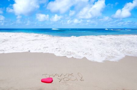 Sign "Thank you" on the sandy beach next to oceanの写真素材