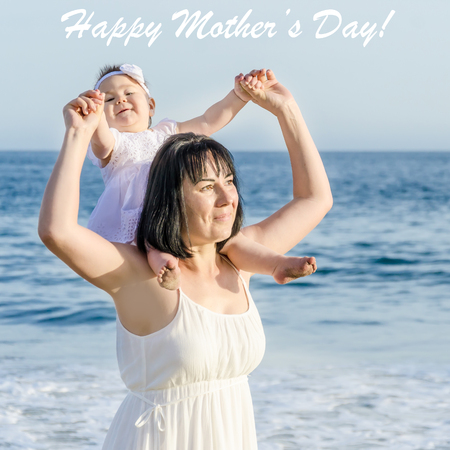 Happy Mother's day background with Mother and daughter on the sandy beach near ocean in sunny dayの写真素材