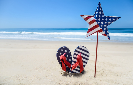 Patriotic USA background with flip flops and decorations on the sandy beachの写真素材