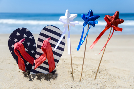 Patriotic USA background with flip flops and decorations on the sandy beachの写真素材