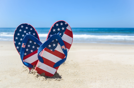 Patriotic USA background with flip flops and decorations on the sandy beachの写真素材