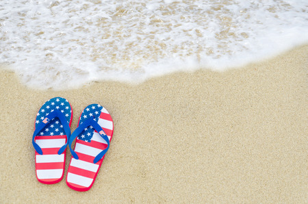 Patriotic USA background with flip flops on the sandy beachの写真素材