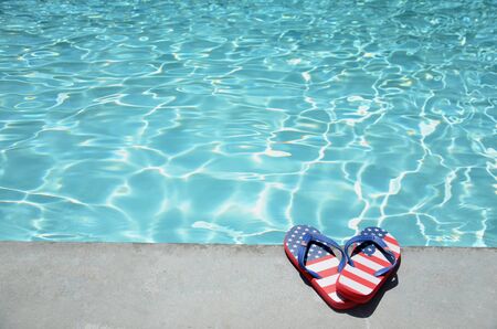 Summer background with flip flops of American flag colors and pattern near the swimming pool