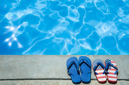 Summer background with flip flops of American flag colors and pattern near the swimming poolの写真素材