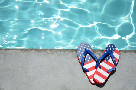 Summer background with flip flops of American flag colors and pattern near the swimming pool