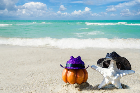 Halloween pumpkin background with starfish in the hat on the sandy beach near the oceanの写真素材