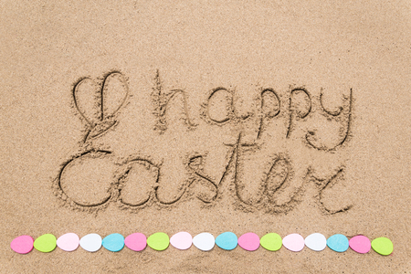 Happy easter background with eggs on the sandy beach near ocean. Hand drawn Happy Easter typography lettering sign.の写真素材