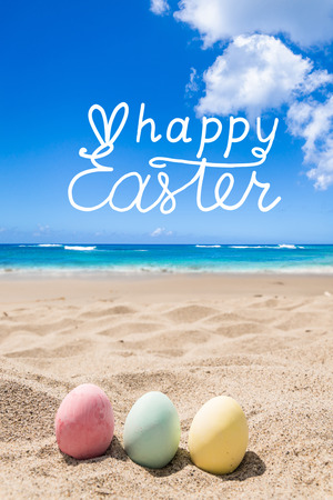 Happy easter background with color eggs on the ocean beach. Hand drawn Happy Easter typography lettering poster.の写真素材