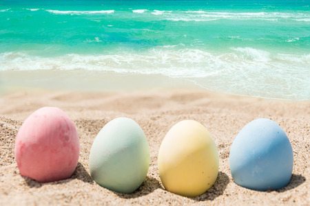 Happy easter background with eggs on the sandy beach near ocean.の写真素材