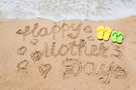 Happy Mother's day background on the sandy beach near the ocean with hearts. Hand drawn lettering typographyの写真素材