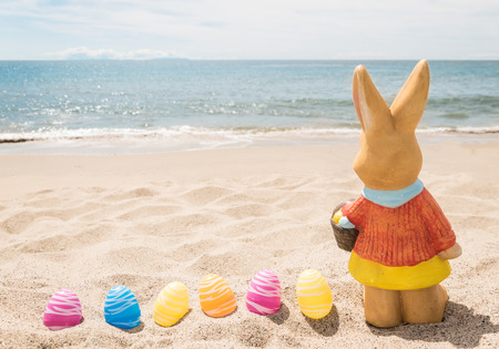 Beach Easter background with bunny and color eggs near oceanの写真素材