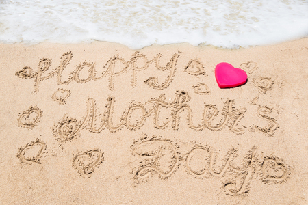 Happy Mother's day background on the sandy beach near the ocean with hearts. Hand drawn lettering typographyの写真素材