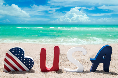 Patriotic USA background with American flag colored heart on the sandy beachの写真素材
