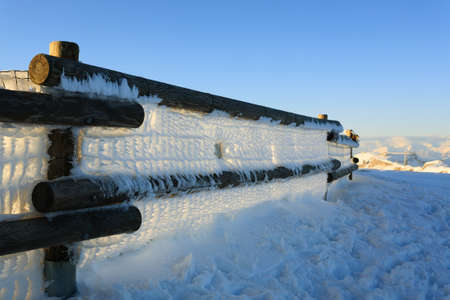 A close up of a fence with frozen snow. Winter panorama from Italian Alpsの写真素材
