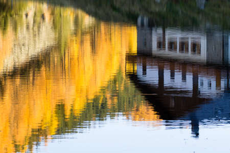 House reflected on water with yellow pines. Autumn panorama. House mirroredの写真素材