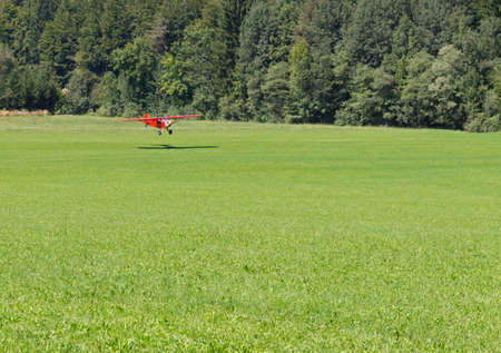Light red aircraft landing on a green meadow, transportation, outdoorの写真素材