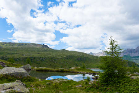 Italian mountain panorama, clouds reflected on alpine lake. Trekking near "Passo San Pellegrino", Italian Alps. Sport and outdoorの写真素材