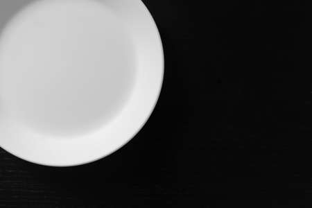 Empty white plate on black wooden table. Kitchen tools close upの写真素材