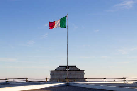 Italian flag on blue sky from first world war memorial in Monte Grappa, Italy. Italian Alps....