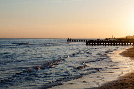 Beach landscape at dawn. Piers perspective view with people. Jesolo beach view, Italian panoramaの写真素材