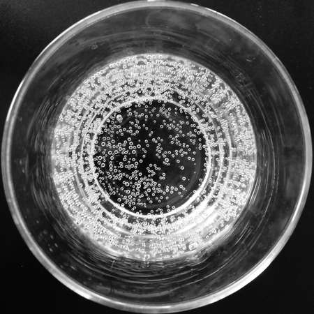 Glass of sparkling water top view. Bubbles texture