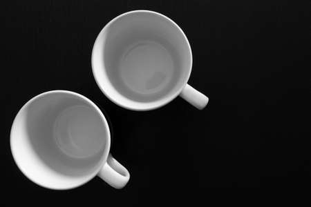 Empty white cups on black wooden table. Kitchen tools close upの写真素材