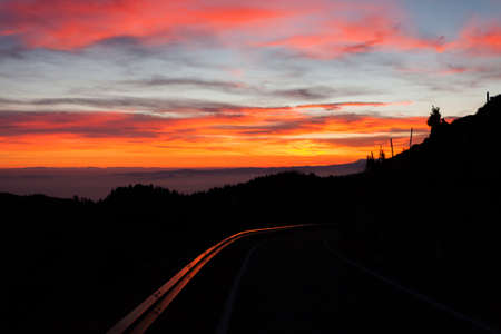 Dramatic red sky with reflections on guard rail road. Darkness landscape