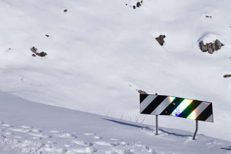 Reflections on traffic sign. Mountain road covered by snow