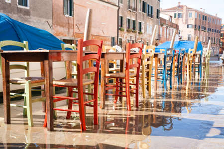 Colorful chairs in a row along Venetian canal. Venice landscape, Italyの写真素材