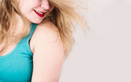 Blonde girl with red lips smiles while her hair flies with the airの写真素材