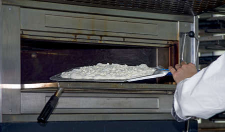 Cooking pizza dough in shovel with electric ovenの写真素材