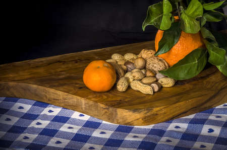 Wooden chopping board with typicals autumnal fruit of citrus and nuts