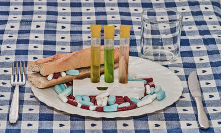 table cloth set with dishes and sandwich stuffed with pills and test tubes with liquid ingredient...